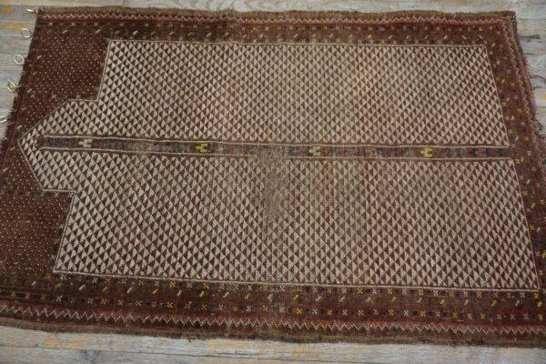 Brown and tan geometric flatweave rug featuring a stepped niche design and dense interlocking triangular motifs on wood flooring.