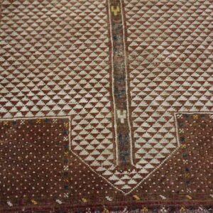 Geometric rug detail showing a rust and cream triangle pattern framed by a dark brown dotted field.