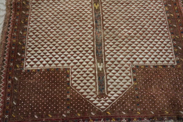 Geometric rug detail showing a rust and cream triangle pattern framed by a dark brown dotted field.
