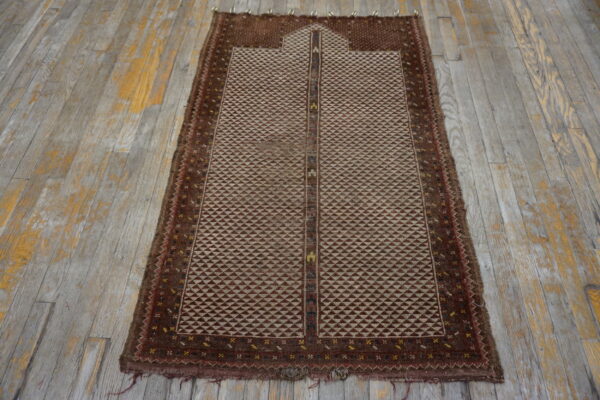 Geometric brown and beige rug with a framed mihrab design shown on worn wooden flooring.