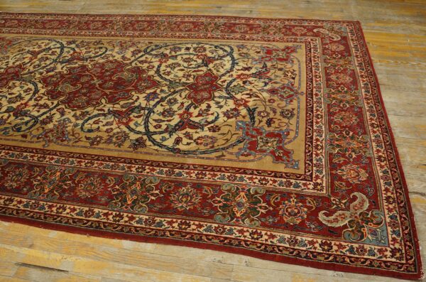 Ornate red and tan patterned rug with scrolling floral and vine motifs displayed on distressed yellow wood flooring.