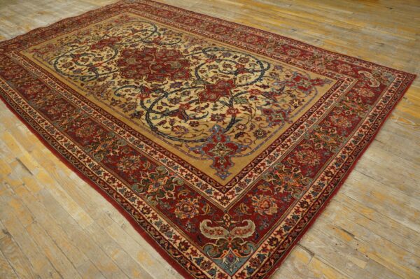 Tan rug with intricate red and blue floral medallions and borders sits on distressed wood floor.