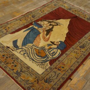Tan, red, and blue pictorial rug depicting two figures, laid diagonally on weathered wood floors.