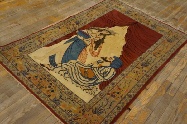Tan, red, and blue pictorial rug depicting two figures, laid diagonally on weathered wood floors.