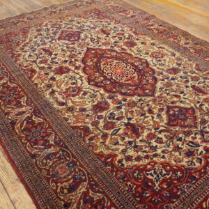 Ornate traditional rug in cream, red, and blue features a central medallion on distressed wood plank flooring.