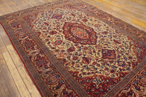Ornate traditional rug in cream, red, and blue features a central medallion on distressed wood plank flooring.