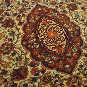 Intricate red and navy central medallion and floral design set on a light beige pile rug.