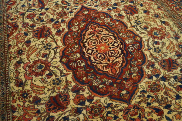Intricate red and navy central medallion and floral design set on a light beige pile rug.