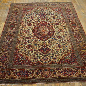Ornate red and beige medallion rug with blue floral accents displayed on distressed wood planks.