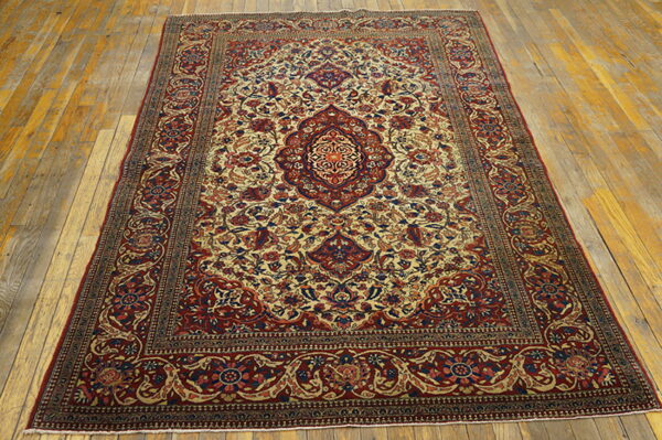 Ornate red and beige medallion rug with blue floral accents displayed on distressed wood planks.