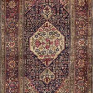 Intricate traditional rug featuring a dark blue central field, a tan medallion, and wide red floral borders.