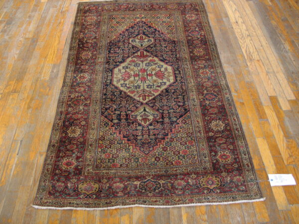 Traditional rug in deep red and navy with a tan central medallion on distressed wood plank flooring.