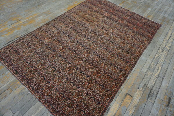 Detailed red, navy, and cream repeating paisley rug covering distressed gray wood floors.