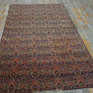 Traditional red, navy, and cream rug with dense patterns rests on weathered gray floorboards.