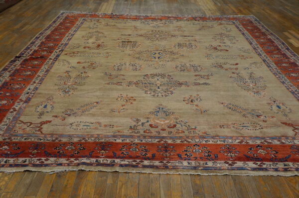 An elaborate pale sage rug with rust and blue floral motifs rests on dark hardwood planks.