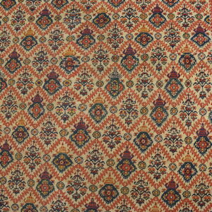 Beige rug featuring an all-over red lattice pattern and repeating navy and red floral designs on wood flooring.