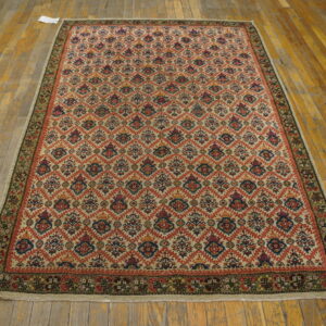 Geometric trellis rug with red and blue accents on a cream field over distressed wood planks.