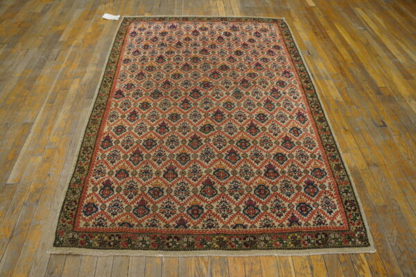 Geometric trellis rug with red and blue accents on a cream field over distressed wood planks.