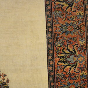 Cream rug field detail alongside a wide, rusty-orange border featuring traditional blue and yellow floral motifs.