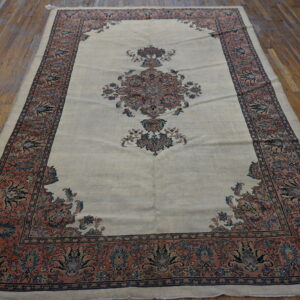 Low-pile cream rug with intricate blue and coral traditional patterns on distressed wood planks.