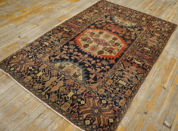 Navy tribal rug with stylized animal motifs and a central beige medallion rests on rustic wood planks.