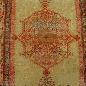 Low-pile rug with a pale gold field, red geometric medallion, and detailed, dark ornamental borders.