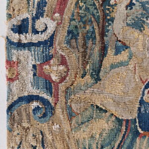 Detailed view of a woven rug with complex patterns in blue, green, tan, and faded red.