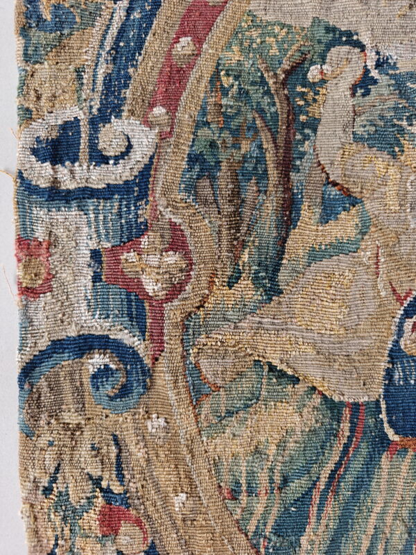 Detailed view of a woven rug with complex patterns in blue, green, tan, and faded red.