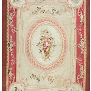 Low pile rug featuring a cream field and decorative pink floral borders and central medallion.
