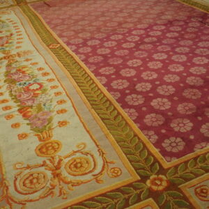 Low-pile rug showing a red floral field and a wide cream border with detailed multicolor flowers and green leaf vines.