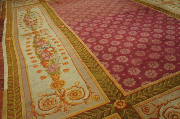 Low-pile rug showing a red floral field and a wide cream border with detailed multicolor flowers and green leaf vines.