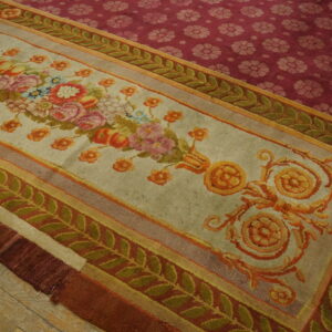 Multi-bordered rug with pastel florals and green vines contrasts with a deep magenta repeating-pattern field on wood flooring.