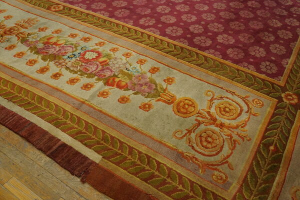 Multi-bordered rug with pastel florals and green vines contrasts with a deep magenta repeating-pattern field on wood flooring.