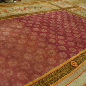 Burgundy rug with repeating light floral motifs and complex floral borders displayed on wood plank flooring.