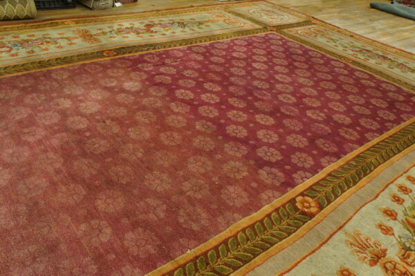 Burgundy rug with repeating light floral motifs and complex floral borders displayed on wood plank flooring.