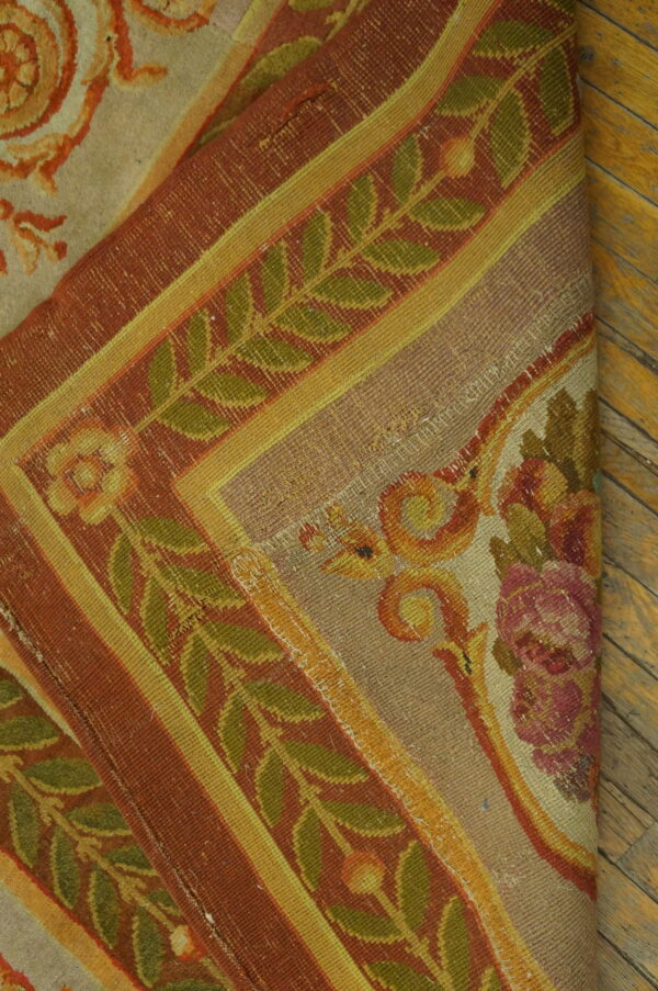 Tightly woven rug featuring rust, olive, and gold botanical borders rests on warm plank wood flooring.