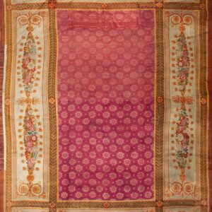 A magenta rug with an allover repeating small floral pattern and a wide ivory border with colorful bouquets.