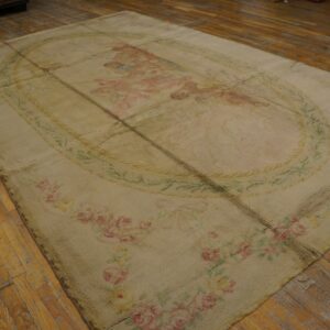 Beige low-pile rug composed of sewn panels features faint pink floral and pictorial designs on distressed wood floors.