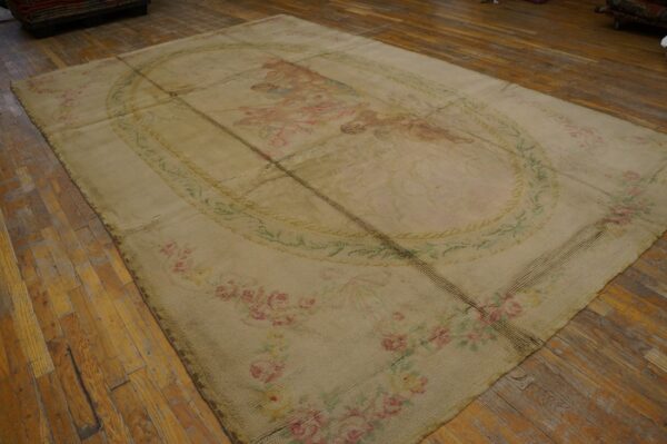 Beige low-pile rug composed of sewn panels features faint pink floral and pictorial designs on distressed wood floors.