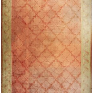 Faded coral rug with a subtle floral trellis pattern and wide distressed beige border design.