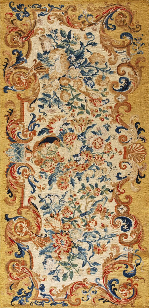 Ornate flat-weave rug featuring a cream floral center surrounded by a golden border of scrolling blue and red patterns.