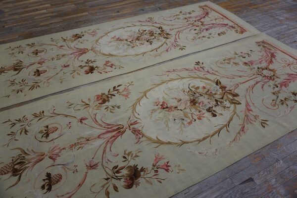 Two matching pale green runners with brown and pink neoclassical floral patterns lie on distressed wood flooring.