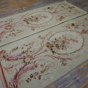 Two light green rugs with detailed pink and brown floral patterns rest on rustic wood flooring.