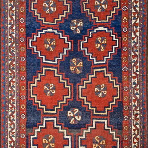 Blue and red rug with serrated diamond medallions and detailed geometric guard borders on a dark field.