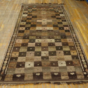 Textured brown, beige, and dark green geometric grid rug displayed on light wooden plank flooring.
