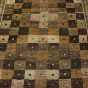 Muted brown and green runner rug with a geometric patchwork grid pattern and a detailed teal border on wood floor.