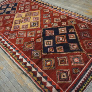 High-pile rug featuring geometric nested squares in red, navy, and yellow on distressed wood planks.
