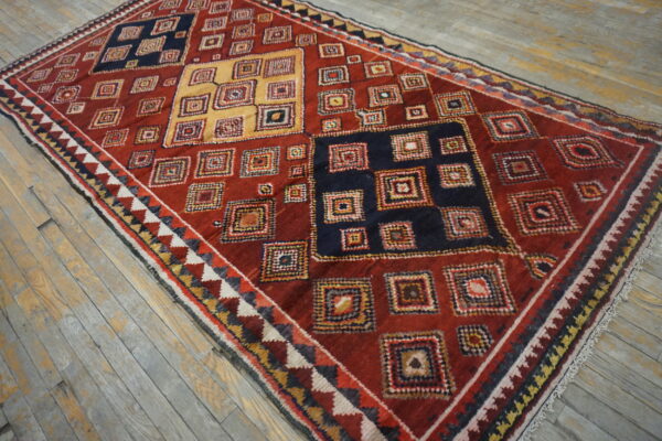 High-pile rug featuring geometric nested squares in red, navy, and yellow on distressed wood planks.