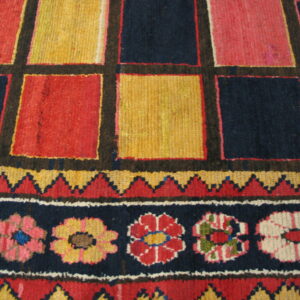 Vibrant geometric rug detail with large squares in red, yellow, and navy above a floral stripe border.