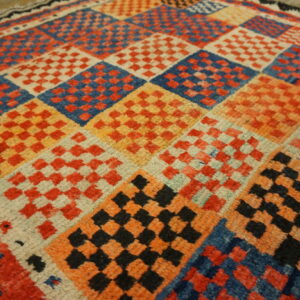 Textured rug with multicolored squares containing smaller red, blue, black, and orange checkerboards.